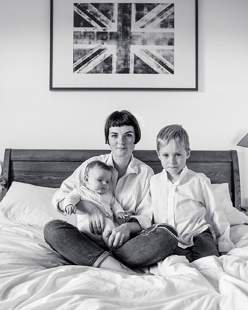 black and white image of siblings sat on bed with union jack poster