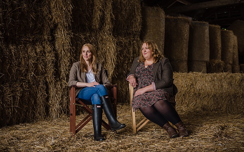 Two female directors sat in haybarn on location photoshoot with Victoria La Bouchardiere