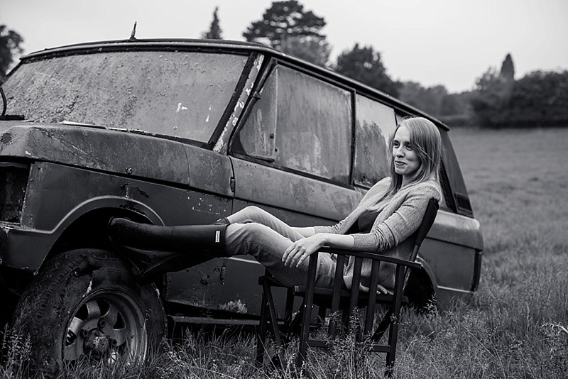 Female sat in directors chair with wellies and old landrover