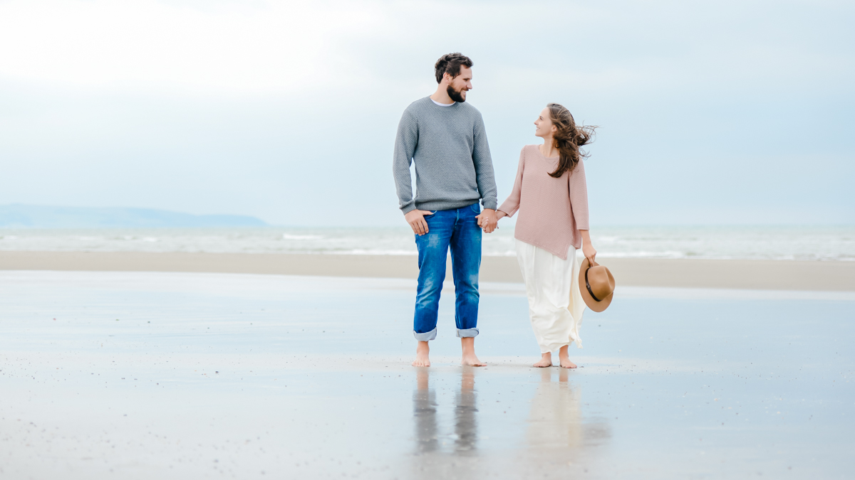 couples holding hands barefoot on beach photographed in Wales by Victoria La Bouchardiere