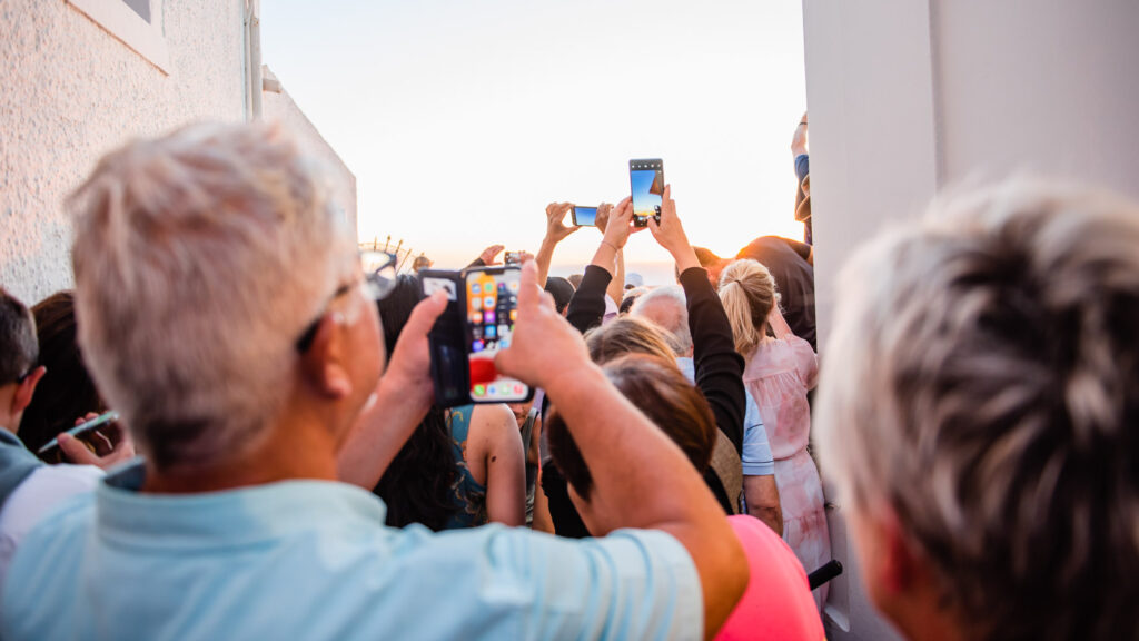 crowd of people using iphones to take picture ofsunset in Santorini