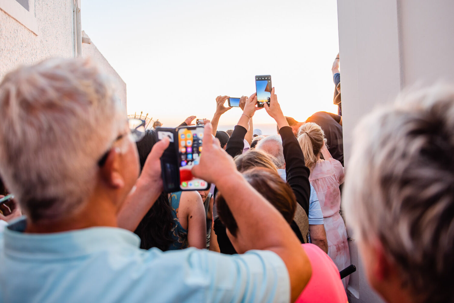 crowd of people using iphones to take picture ofsunset in Santorini