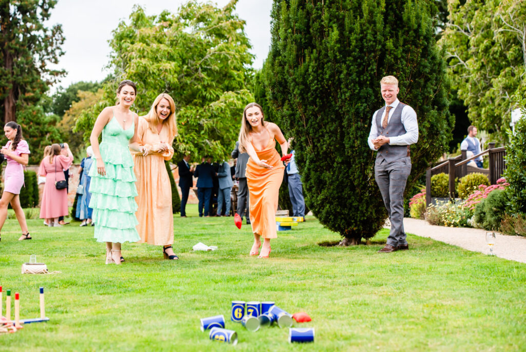 wedding guests in orange and green dresses playing garden games