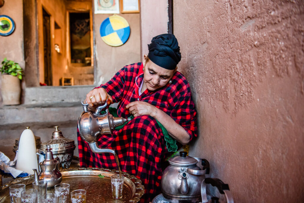 Berber woman in black and red dress pouring green tea