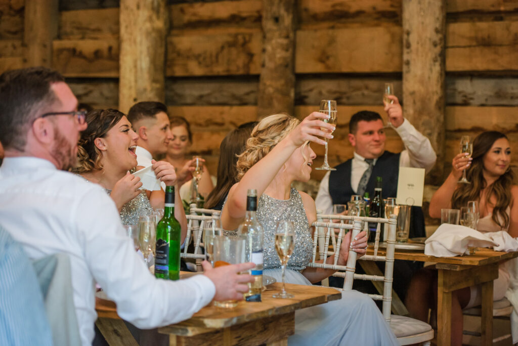 wedding guests raising a toast during speeches at Pimhill Barn wedding venue