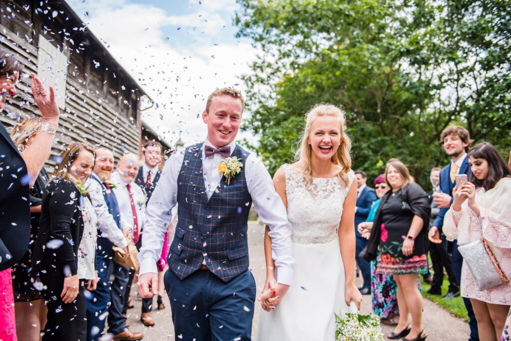Bride and groom walking through a confetti tunnel at Pimhill Barn wedding venue