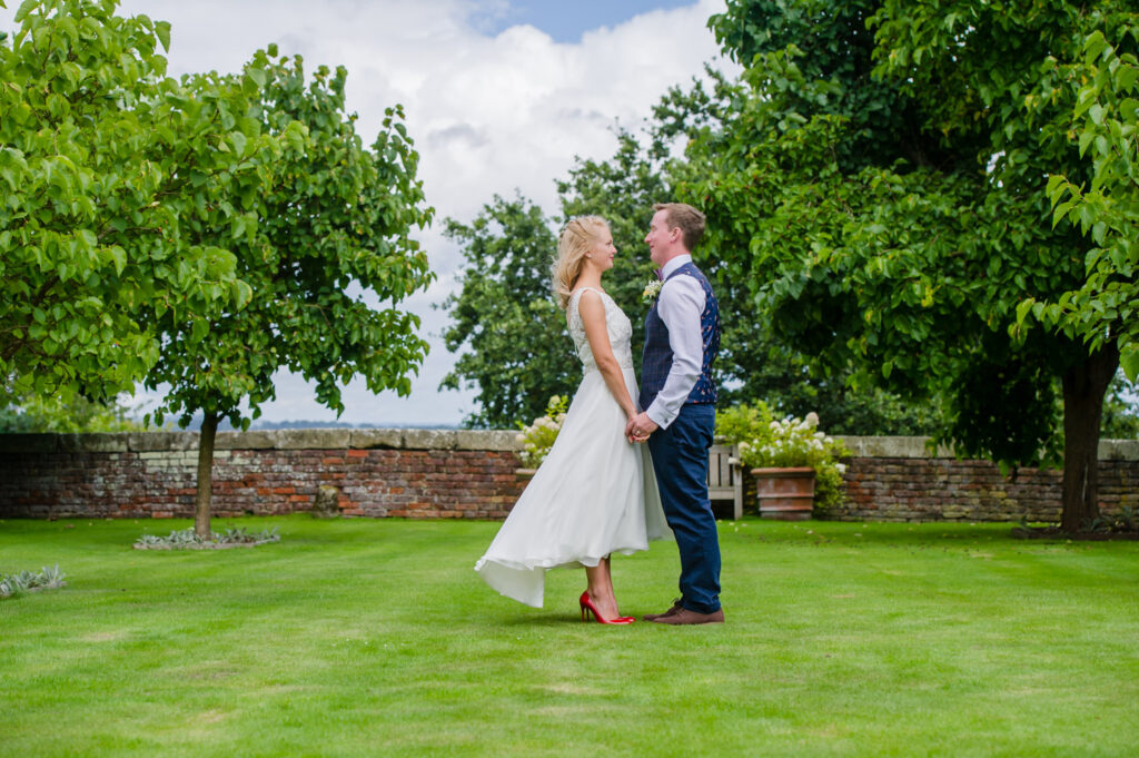 Bride and groom facing each other holding hands on the lawn at Pimhill wedding venue
