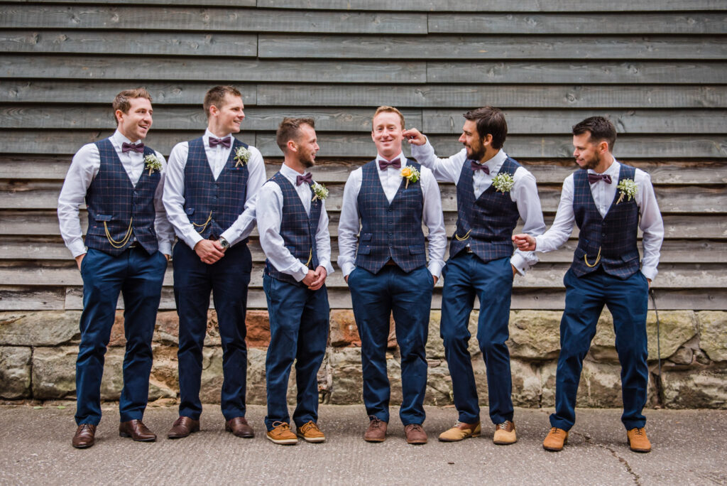 Groom and groomsmen in navy blue suits standing in front of barn at Pimhill Barn